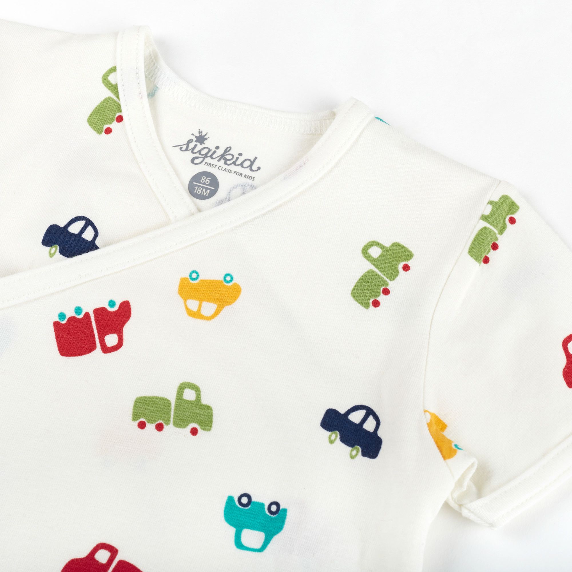 Nahaufnahme Babybody, weiß mit bunten Auto-Motiven. Marke sigikid. Wickeloptik, kurze Ärmel.