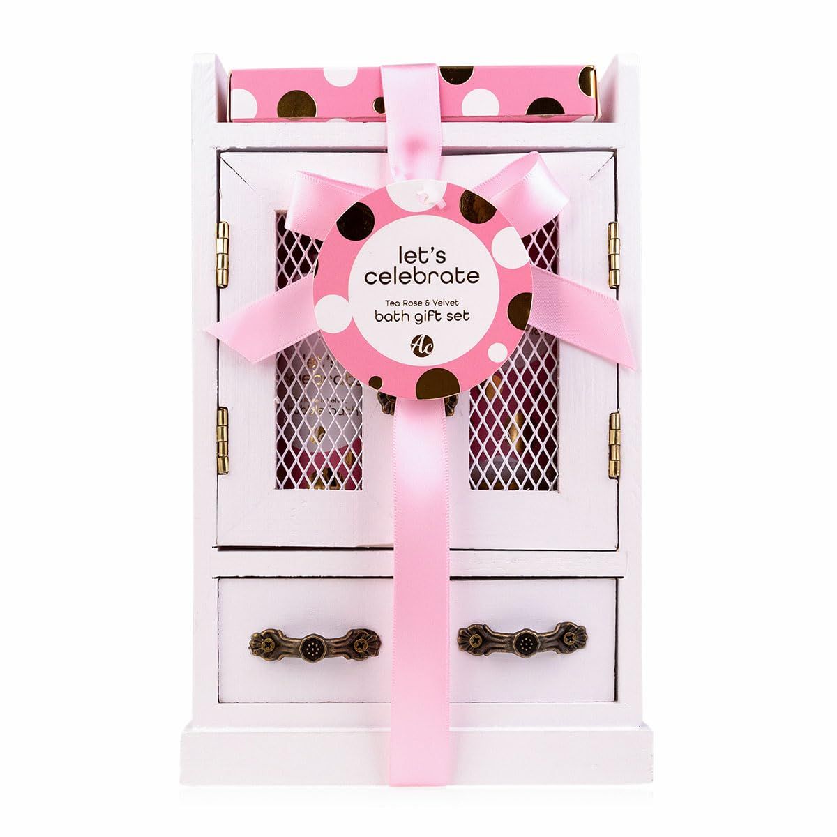 Geschenkset in weißem Schrank, mit rosa Schleife und Anhänger. Enthält rosa Produkte mit weißen und goldenen Punkten. Geschlossen.