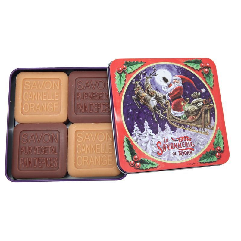 Metallbox mit Seife. Vier Seifenstücke in einer geöffneten Dose. Auf der Dose ist ein Weihnachtsmotiv mit Santa Claus und Rentieren abgebildet.