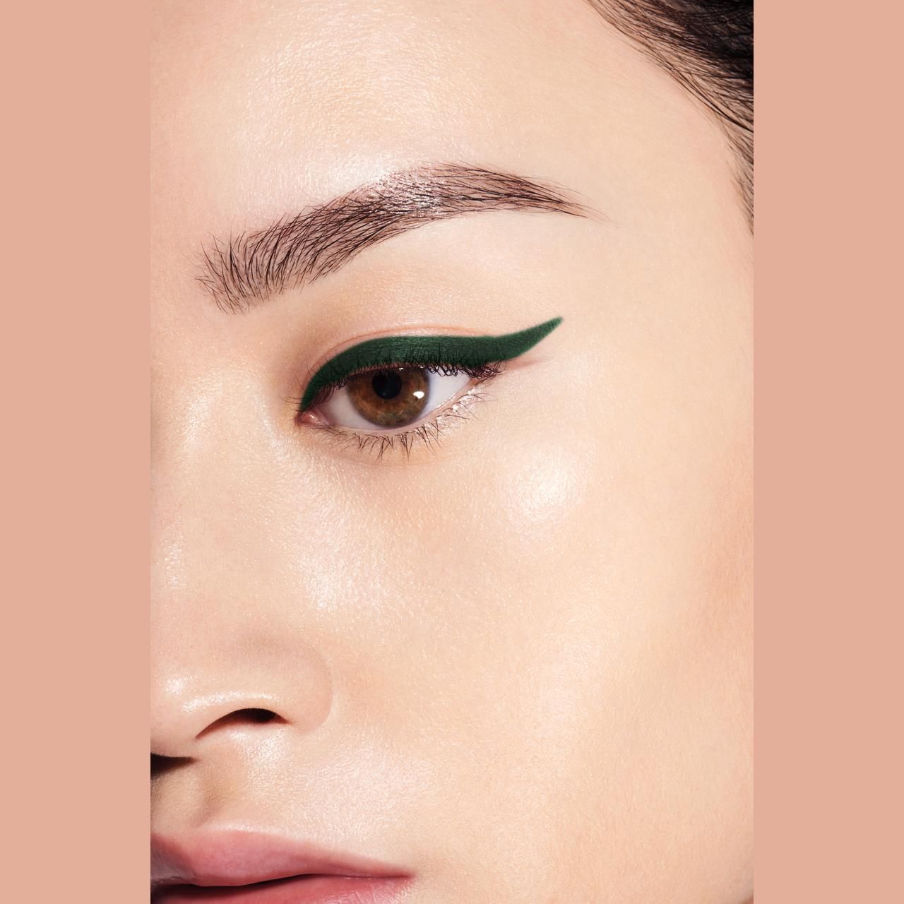 Auge mit grünem Eyeliner. Braune Augen, Hautton. Eyeliner-Strich entlang des oberen Wimpernkranzes.