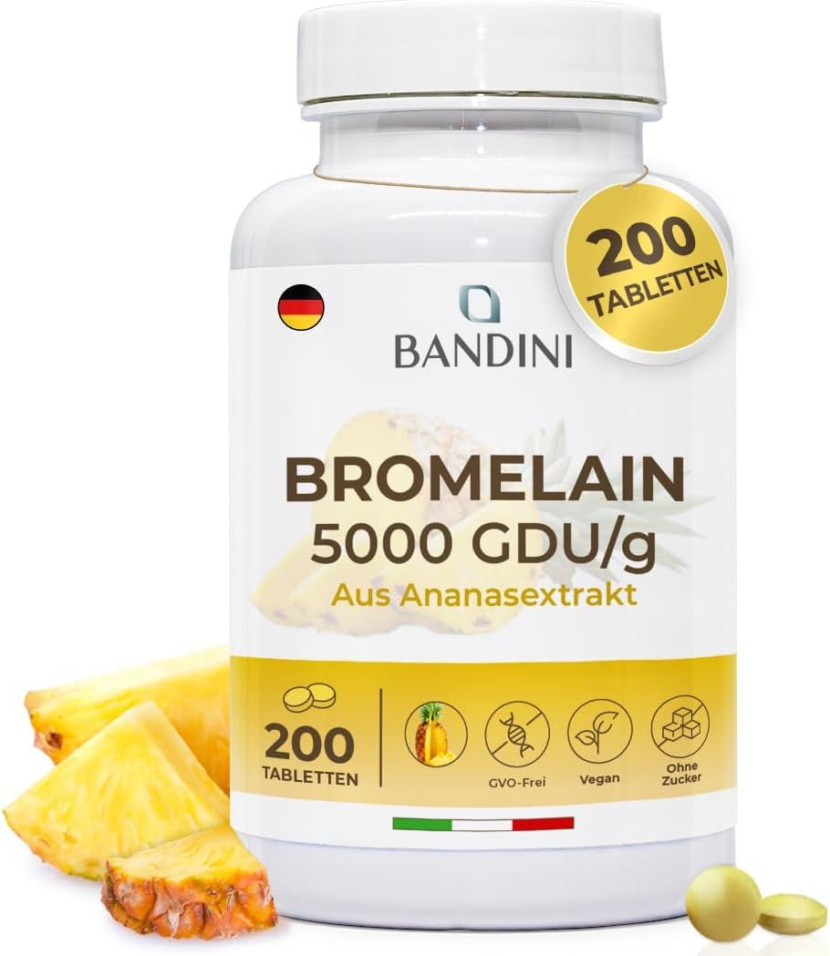 Weiße Flasche Bandini Bromelain Tabletten. Aufschrift: Bromelain 5000 GDU/g. 200 Tabletten. Ananasstücke und Tabletten daneben.