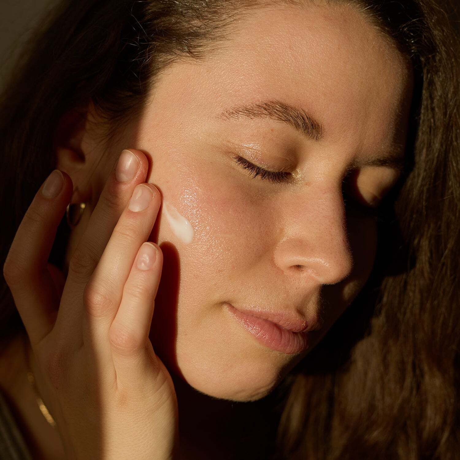 Frau trägt Creme auf ihr Gesicht auf. Hautnahaufnahme. Sonnencreme wird auf die Haut aufgetragen.