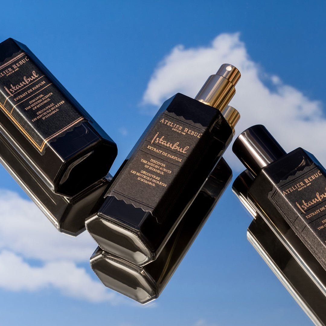 Drei schwarze Flakons mit goldfarbenen Verschlüssen. Aufschrift "Istanbul Extrait de Parfum". Reflektierende Oberfläche.