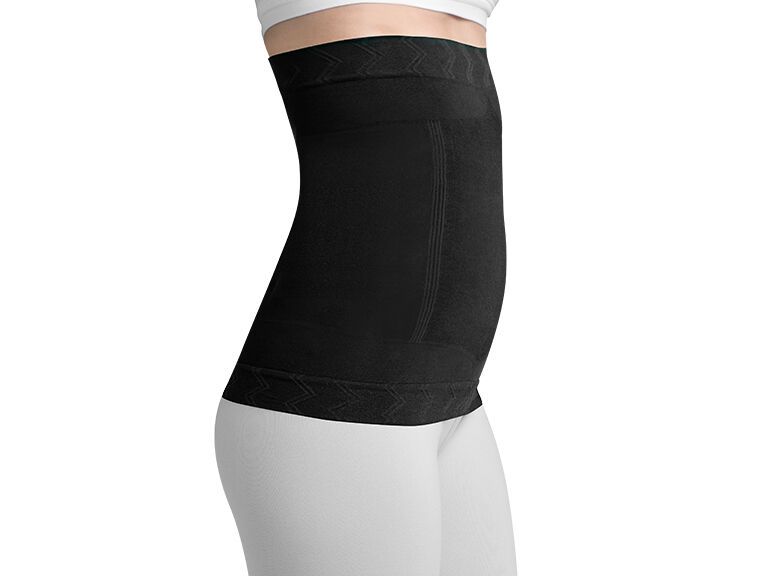 Schwarze, bauchhohe Bandage. Seitliche Ansicht. Geformtes Material. Trägerin in weißer Kleidung.