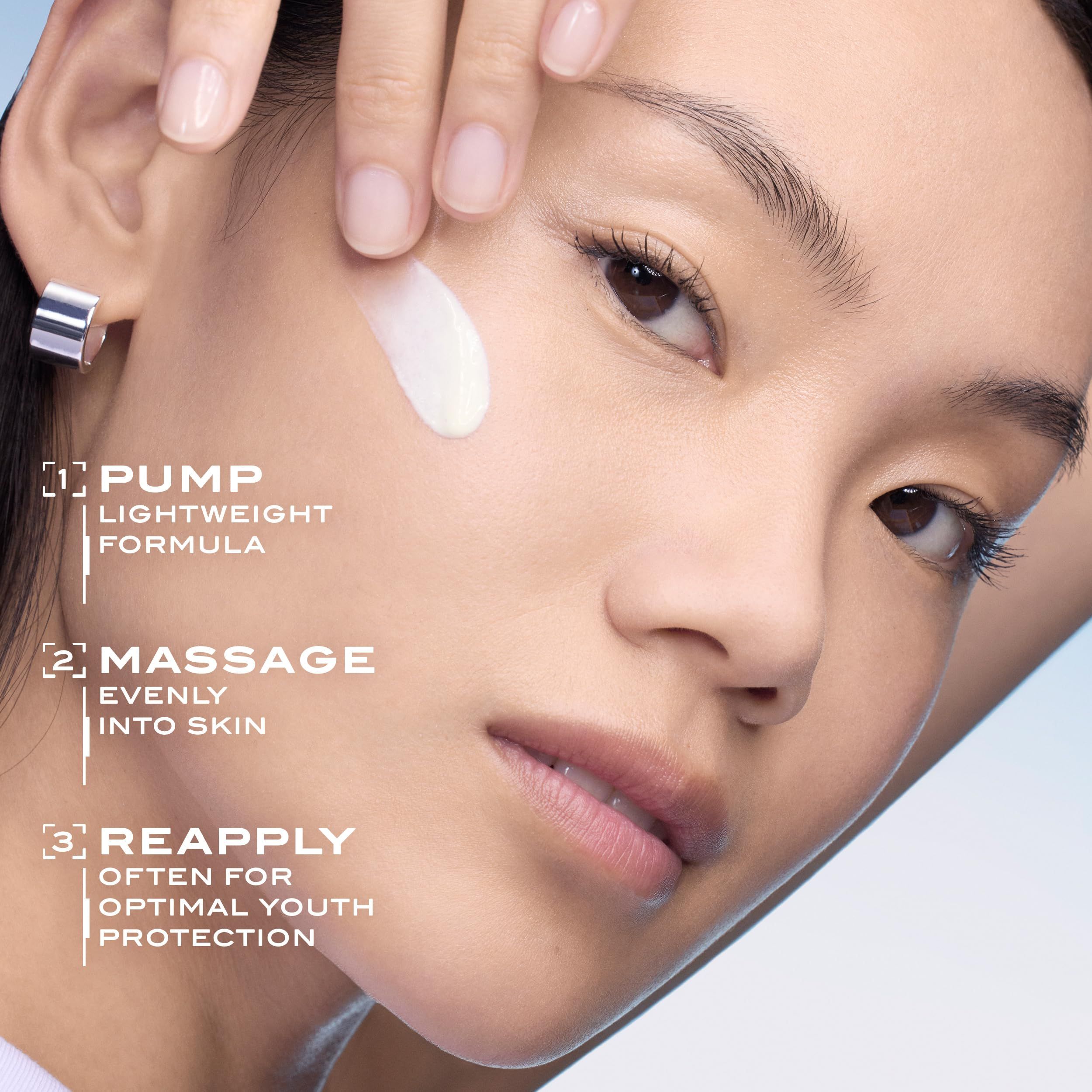 Eine Hand trägt eine weiße Creme auf die Wange einer Frau auf. Anleitungsstufen: 1. Pumpen, leichte Formel. 2. In die Haut einmassieren. 3. Wiederholen für optimalen Jugendschutz.