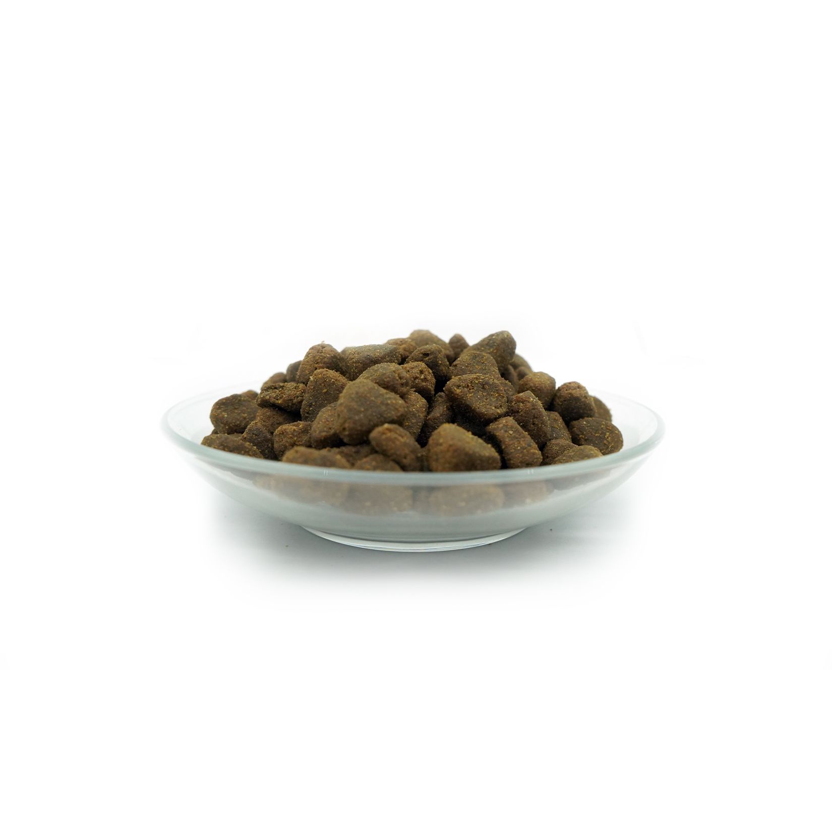 Hundefutter-Trockenfutter in einer Glasschale. Braune, unregelmäßig geformte Kroketten.