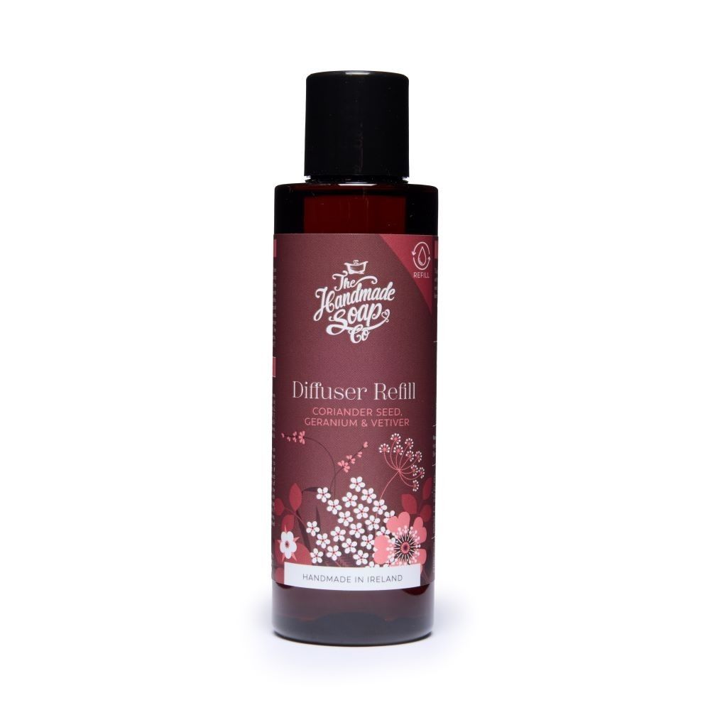 Braune Flasche mit schwarzem Deckel. Aufschrift: Diffuser Refill, Koriandersamen, Geranium & Vetiver. Blumenmuster.