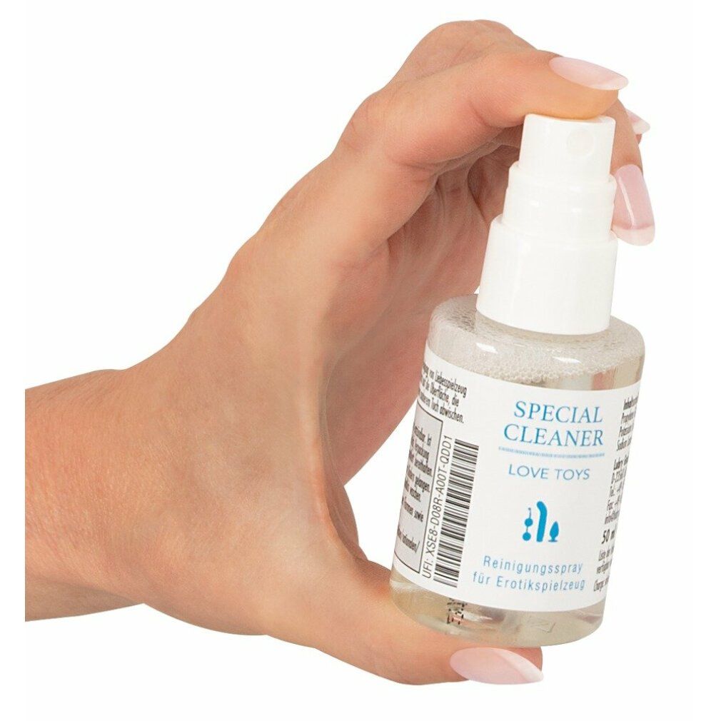 Hand hält eine kleine, transparente Sprühflasche mit weißem Sprühkopf. Aufschrift: SPECIAL CLEANER LOVE TOYS. Reinigungsspray.