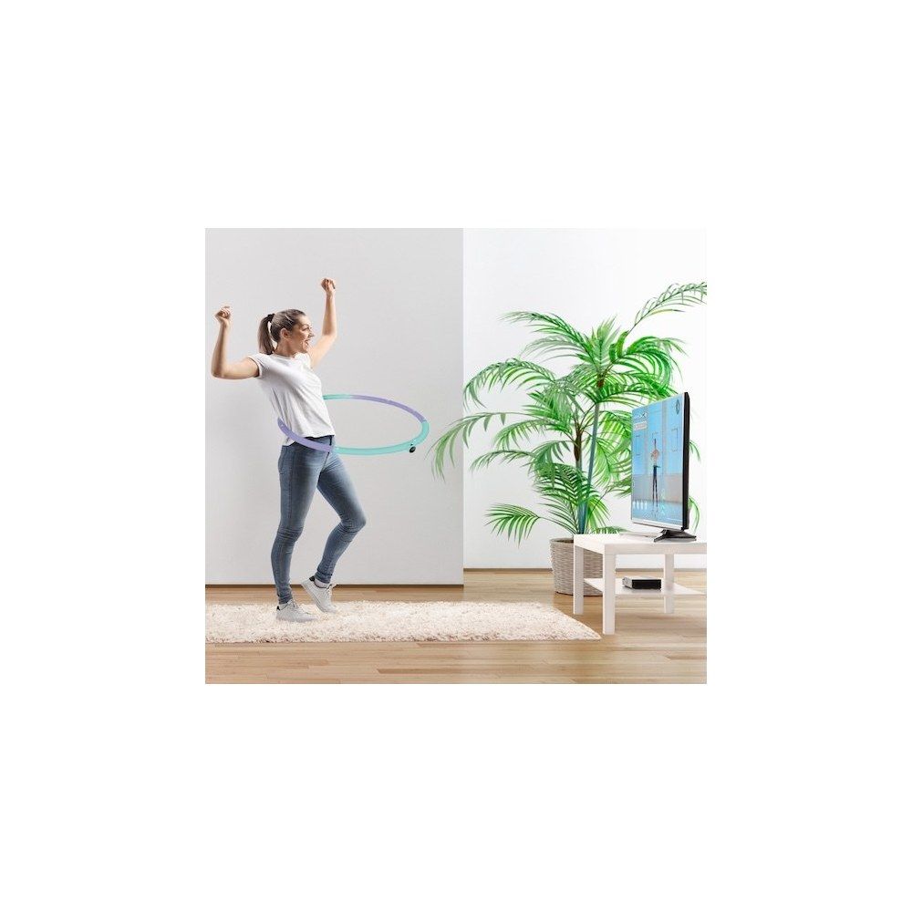 Frau trainiert mit einem Hula-Hoop-Reifen in einem hellen Raum vor einem Fernseher.