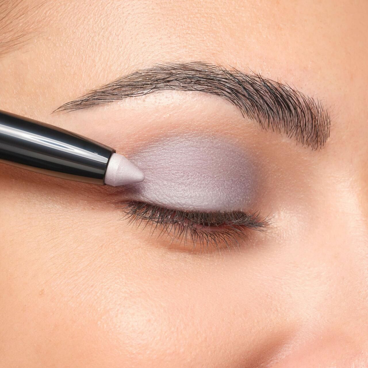 Auge mit aufgetragenem Lidschatten. Ein Artdeco High Performance Eyeshadow Stylo wird verwendet. Augenbraue sichtbar.