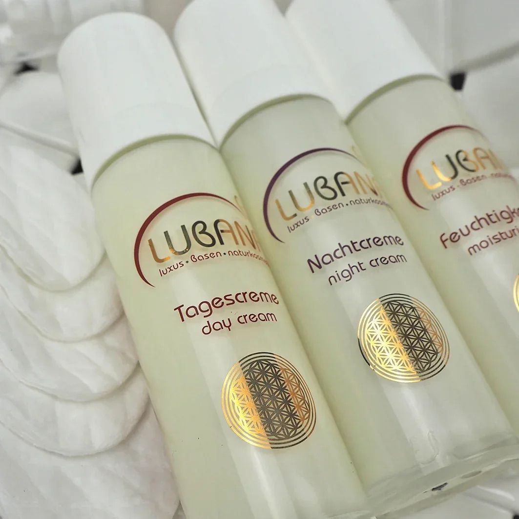 Drei Creme-Flakons mit weißem Deckel. Aufschrift: Lubana Tagescreme, Nachtcreme und Feuchtigkeitspflege. Goldfarbenes Symbol.