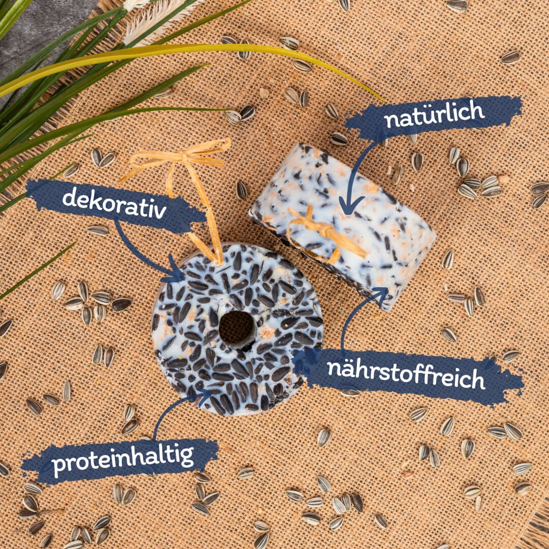 Zwei Futterringe und ein Futterblock mit Sonnenblumenkernen. Auf Leinenstoff, mit Text-Labels.