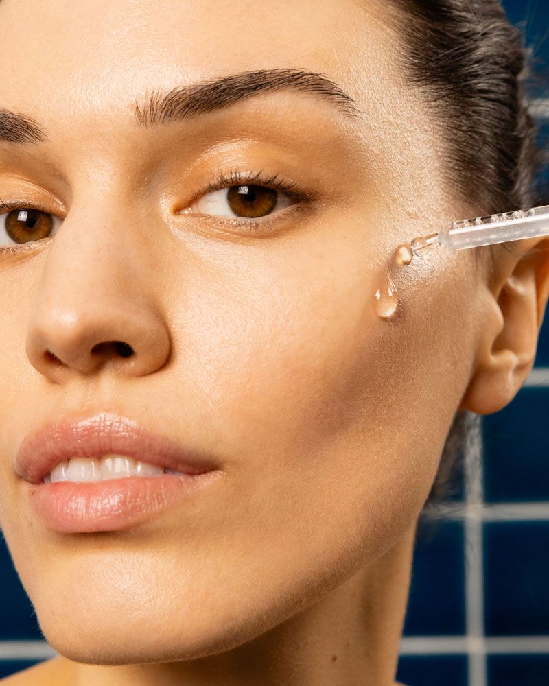 Nahaufnahme einer Frau, die Serum mit einer Pipette auf die Haut aufträgt. Tropfen Serum auf der Haut.