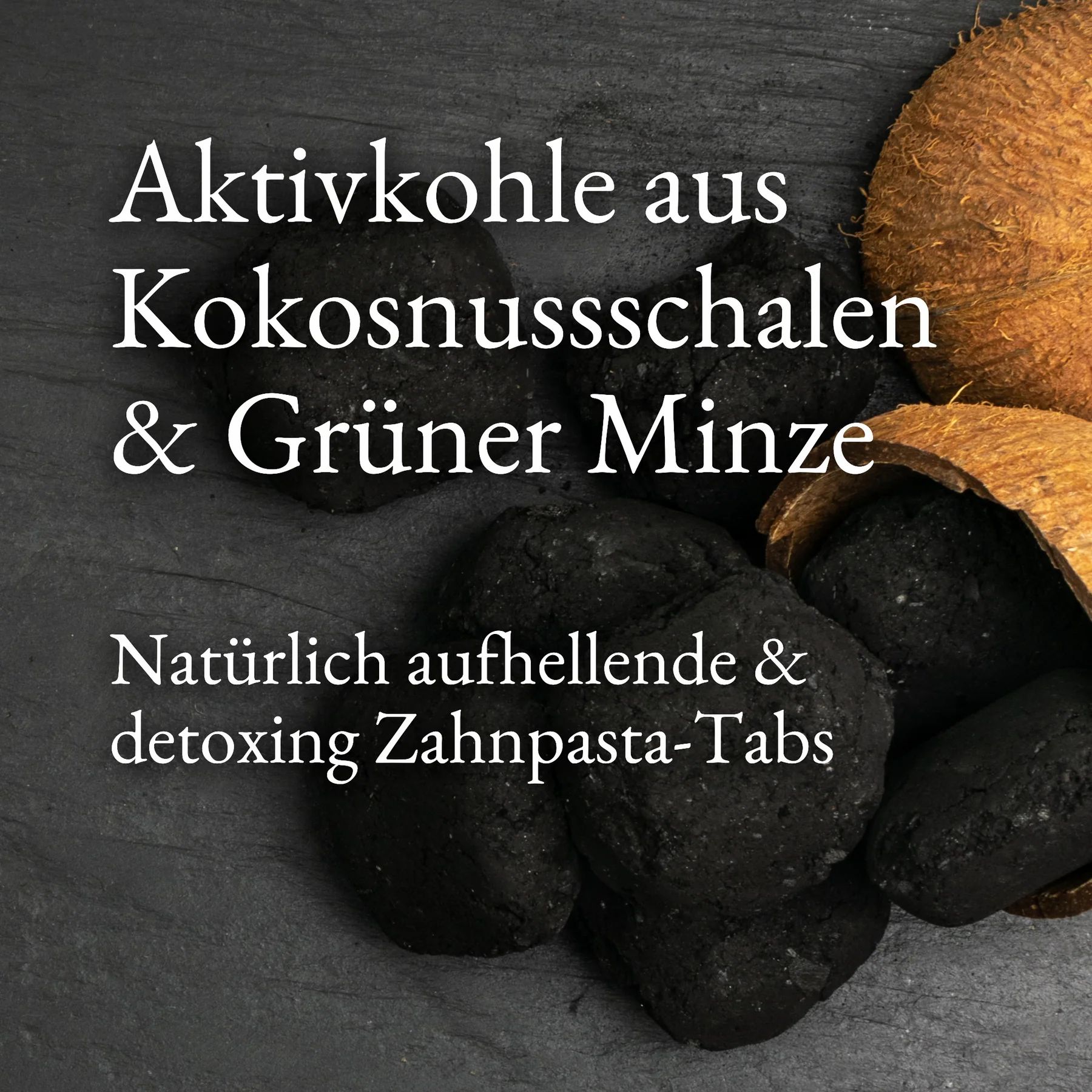 Eine Ansammlung von schwarzen, runden Zahnpasta-Tabs aus Aktivkohle aus Kokosnussschalen & Grüner Minze. Daneben ein Stück Kokosnussschale. Der Text lautet: Natürlich aufhellende & detoxing Zahnpasta-Tabs.