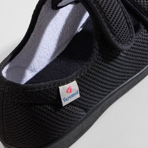 Nahaufnahme des Varomed-Logos auf schwarzen Mesh-Sandalen.