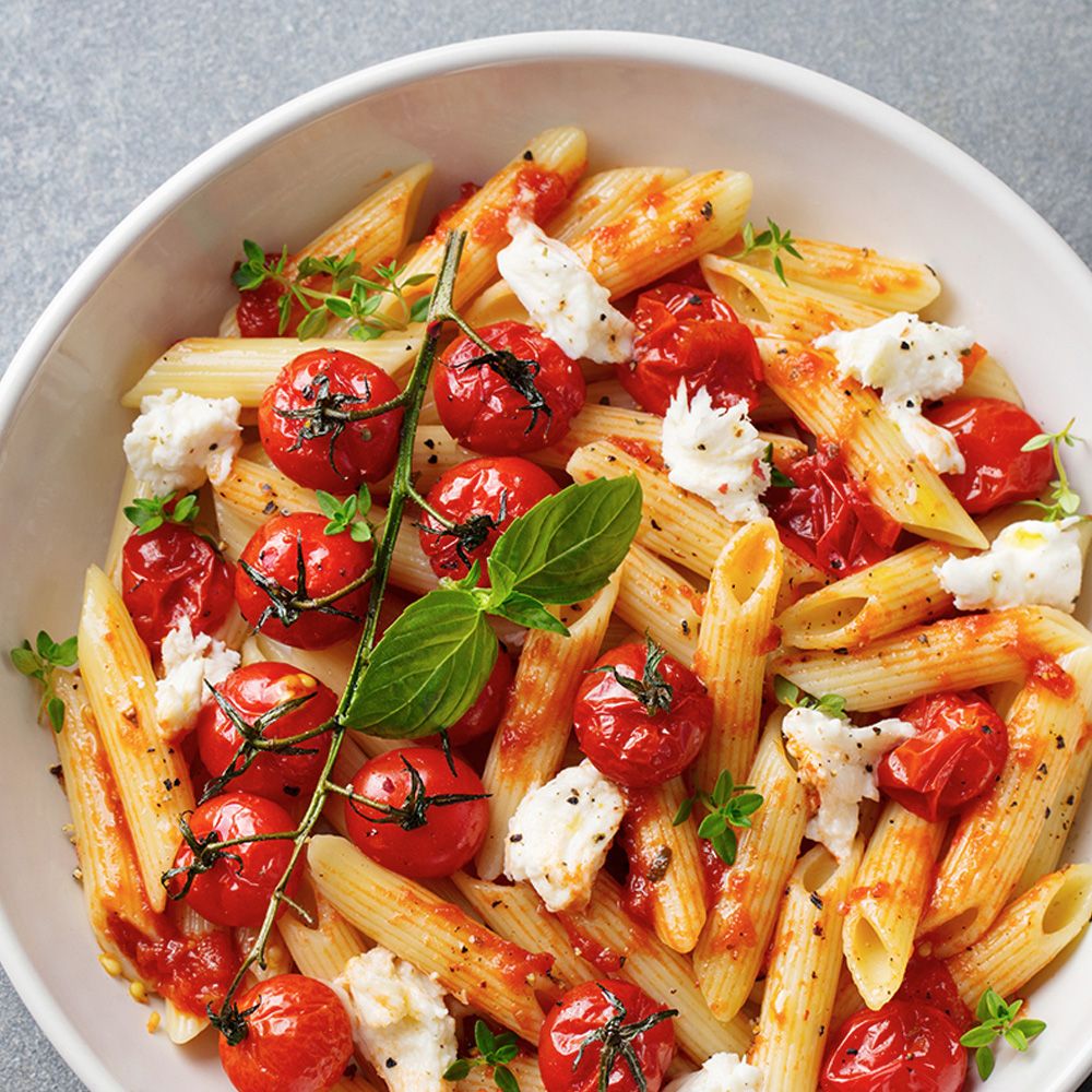 Pasta mit Tomaten, Mozzarella und Kräutern in weißer Schüssel. Draufsicht.