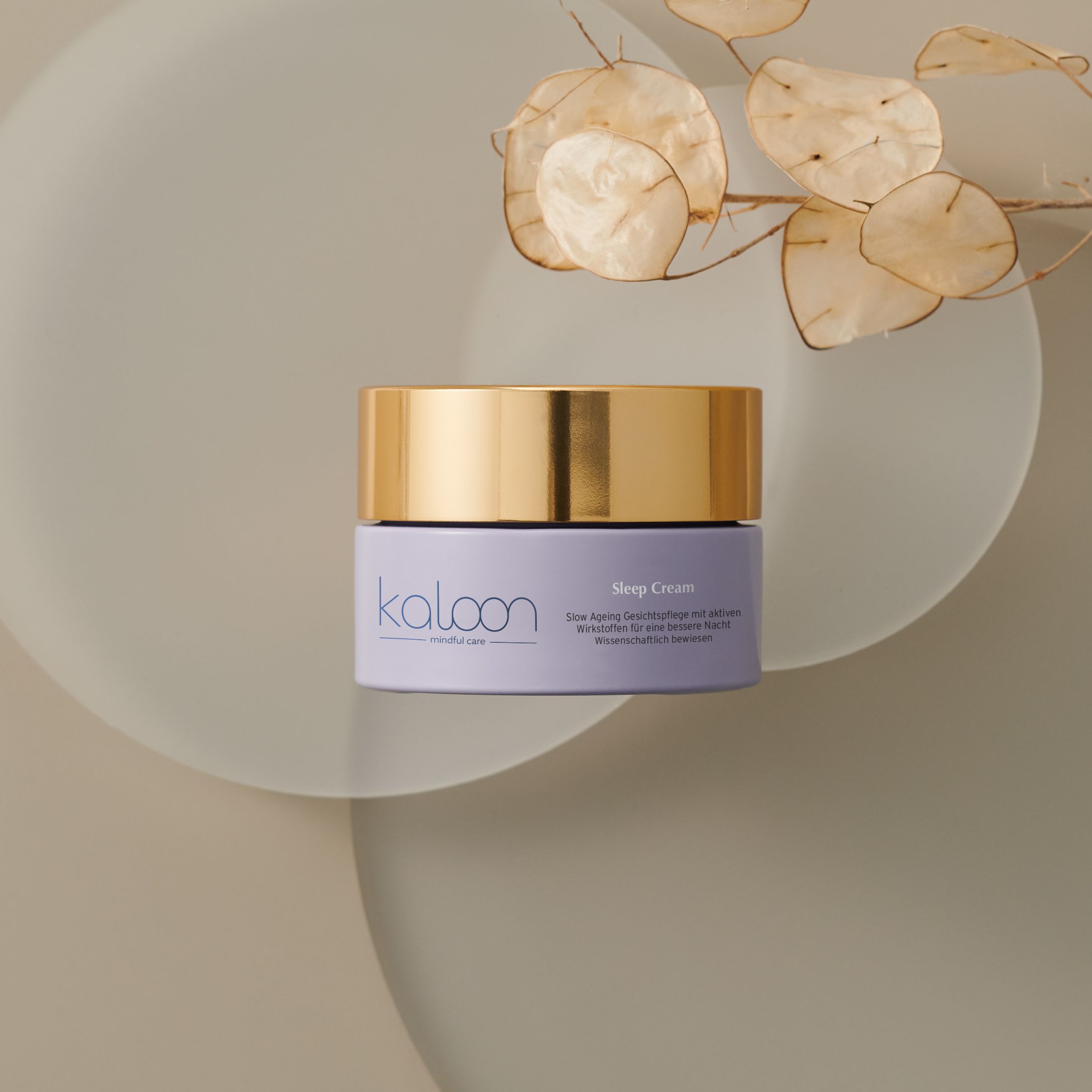 Creme-Tiegel mit goldfarbenem Deckel auf einer Oberfläche. Auf dem Etikett steht "kaloon" und "Mindful Care".