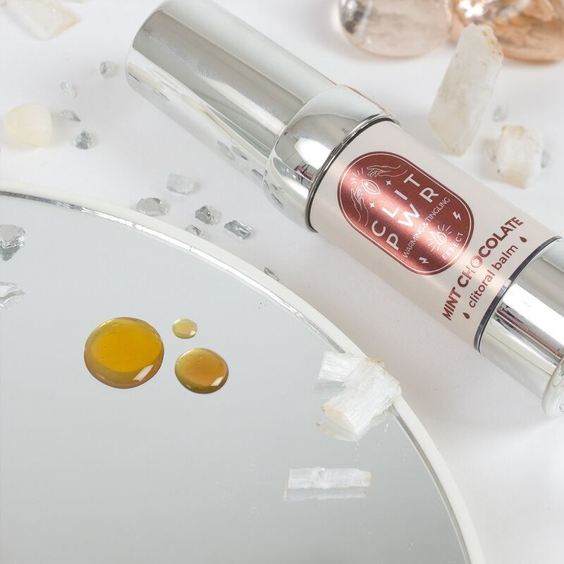 Zylinderförmiges Produkt mit silberner Kappe. Auf einer runden Spiegelfläche. Daneben Flüssigkeitstropfen.