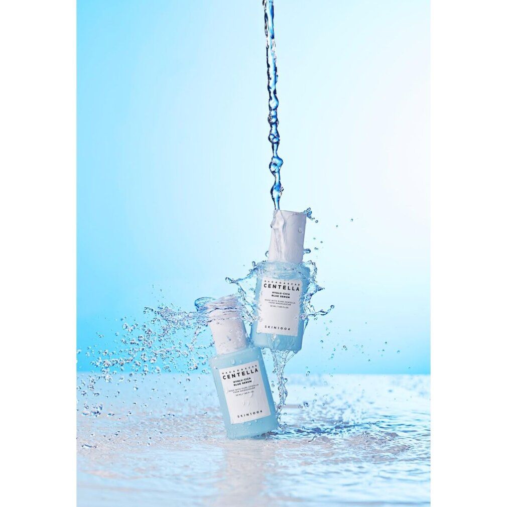 Wasserstrahl mit Serumfläschchen. Beschriftung: MADAGASCAR CENTELLA HYALU-CICA BLUE SERUM. SKIN1004.
