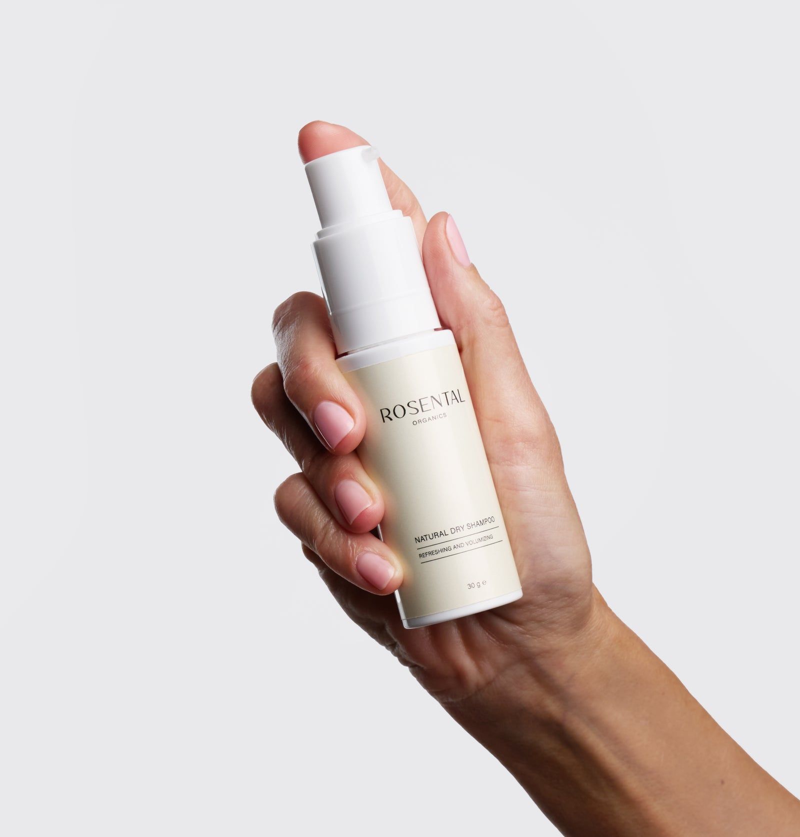 Hand hält eine weiße Flasche Trockenshampoo. Aufschrift: Rosental Organics, Natural Dry Shampoo.