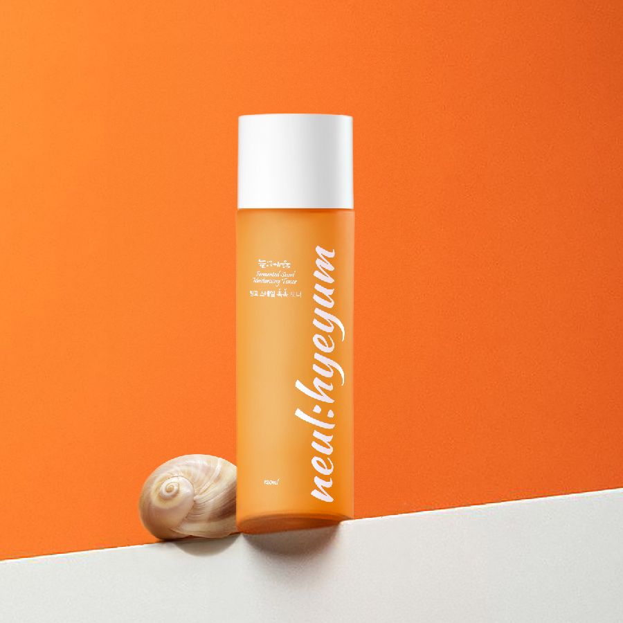 Orangefarbene Flasche mit weißem Deckel und Schneckenhaus. Aufschrift "neul:hyeyum" in weißer Schrift.