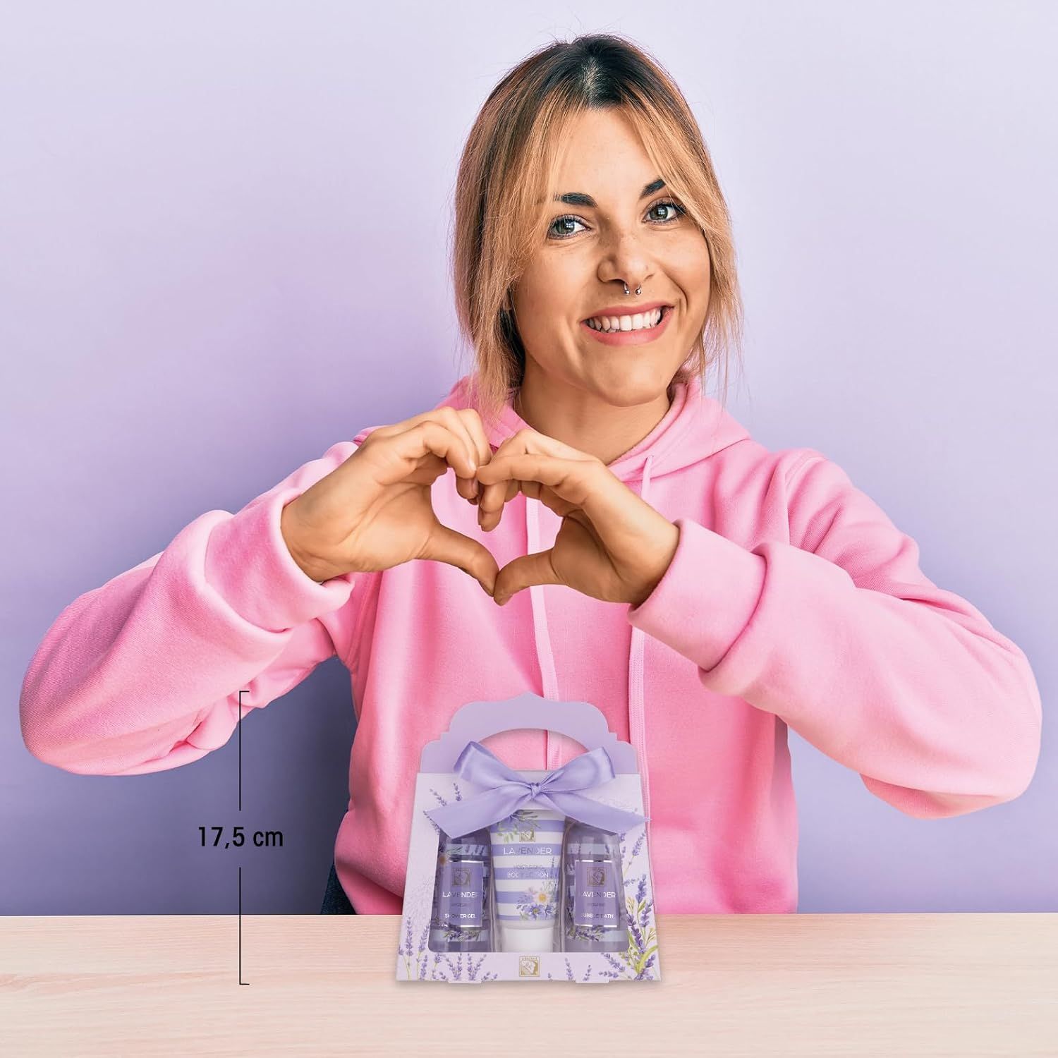 Frau hält Herzform mit Händen. Geschenkset mit Duschgel, Schaumbad und Bodylotion auf Tisch.