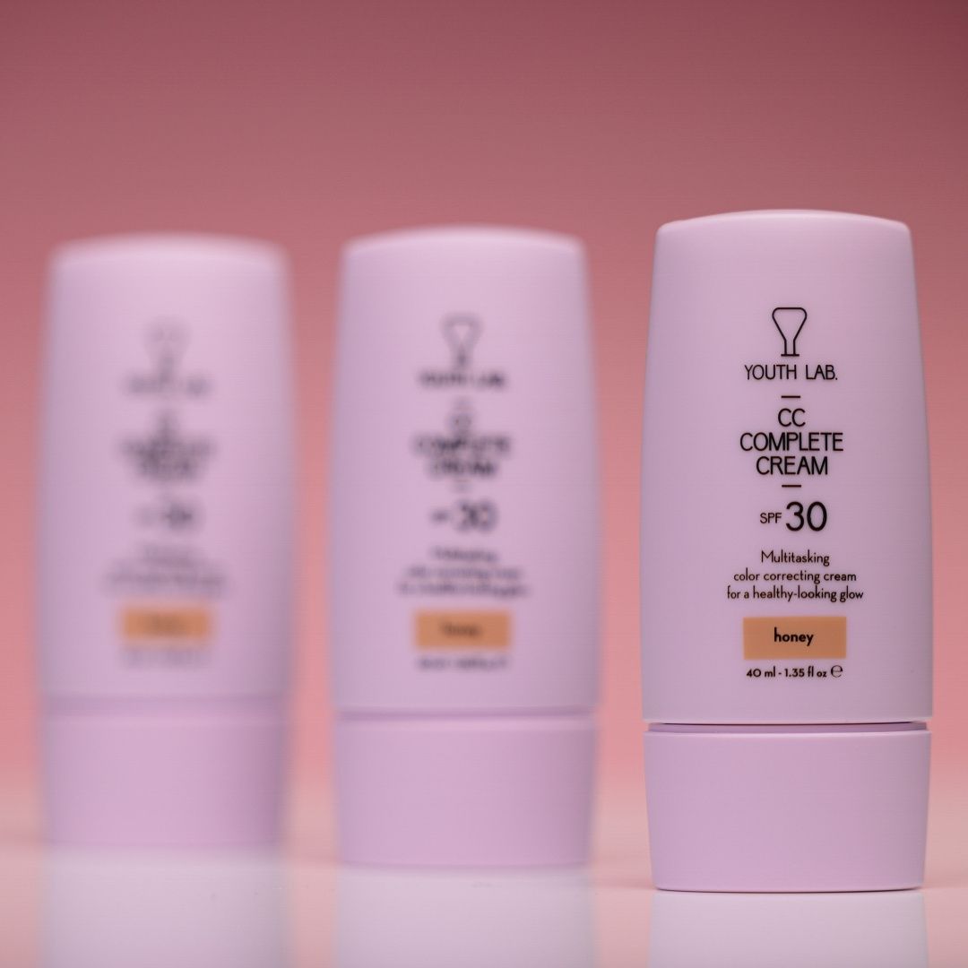 Drei Tuben YOUTH LAB CC Complete Cream Honey. Rosa Tuben mit weißem Text. Text: CC Complete Cream, SPF 30, Honey. Aufschrift YOUTH LAB.