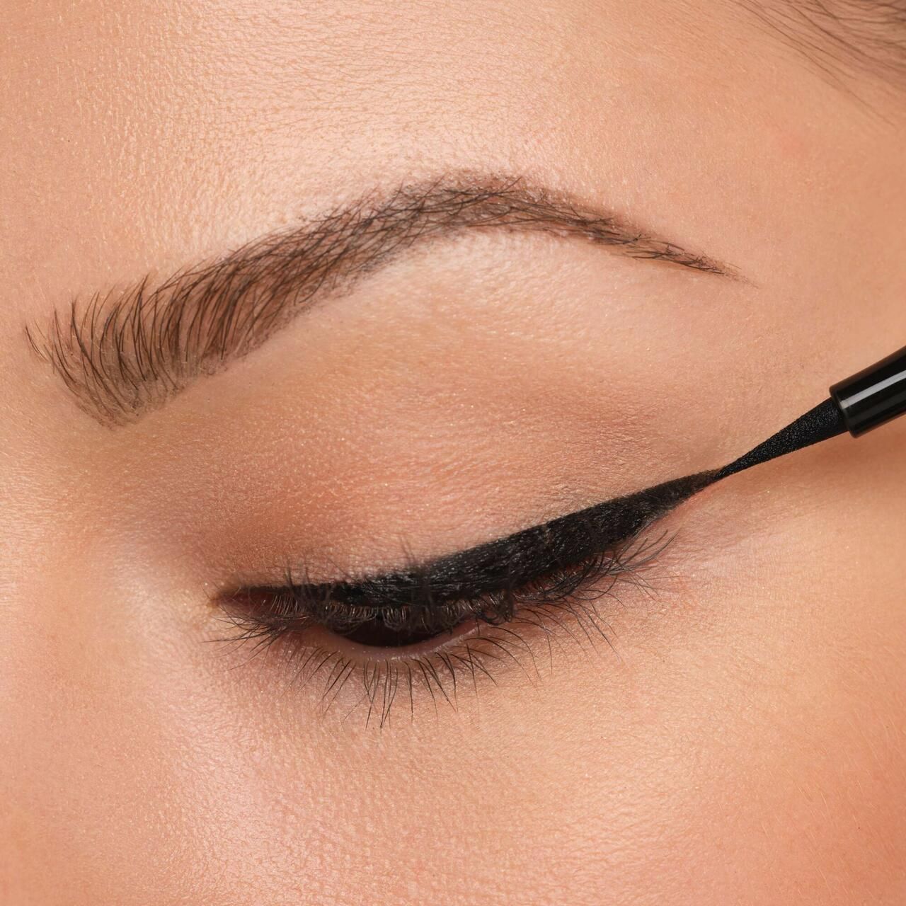 Auge mit Lidstrich. Schwarzer Eyeliner wird aufgetragen.