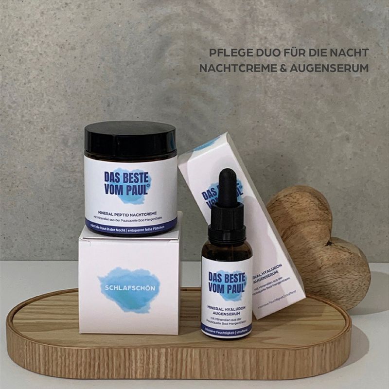 Zwei Kosmetikprodukte auf Holztablett. Creme-Tiegel, Serumflasche und zwei Kartons. Text: DAS BESTE VOM PAUL, Schlafschoen.