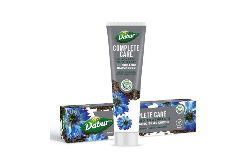 Dabur Complete Care Schwarzkümmel Zahnpasta Tube und zwei Faltschachteln mit Blaue-Kornblumen-Motiv.