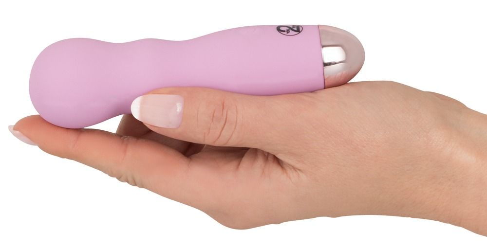 Mini-Vibrator in Hand gehalten. Rosa, zylindrisch, silberfarbene Spitze. Wellenförmiger Griff.