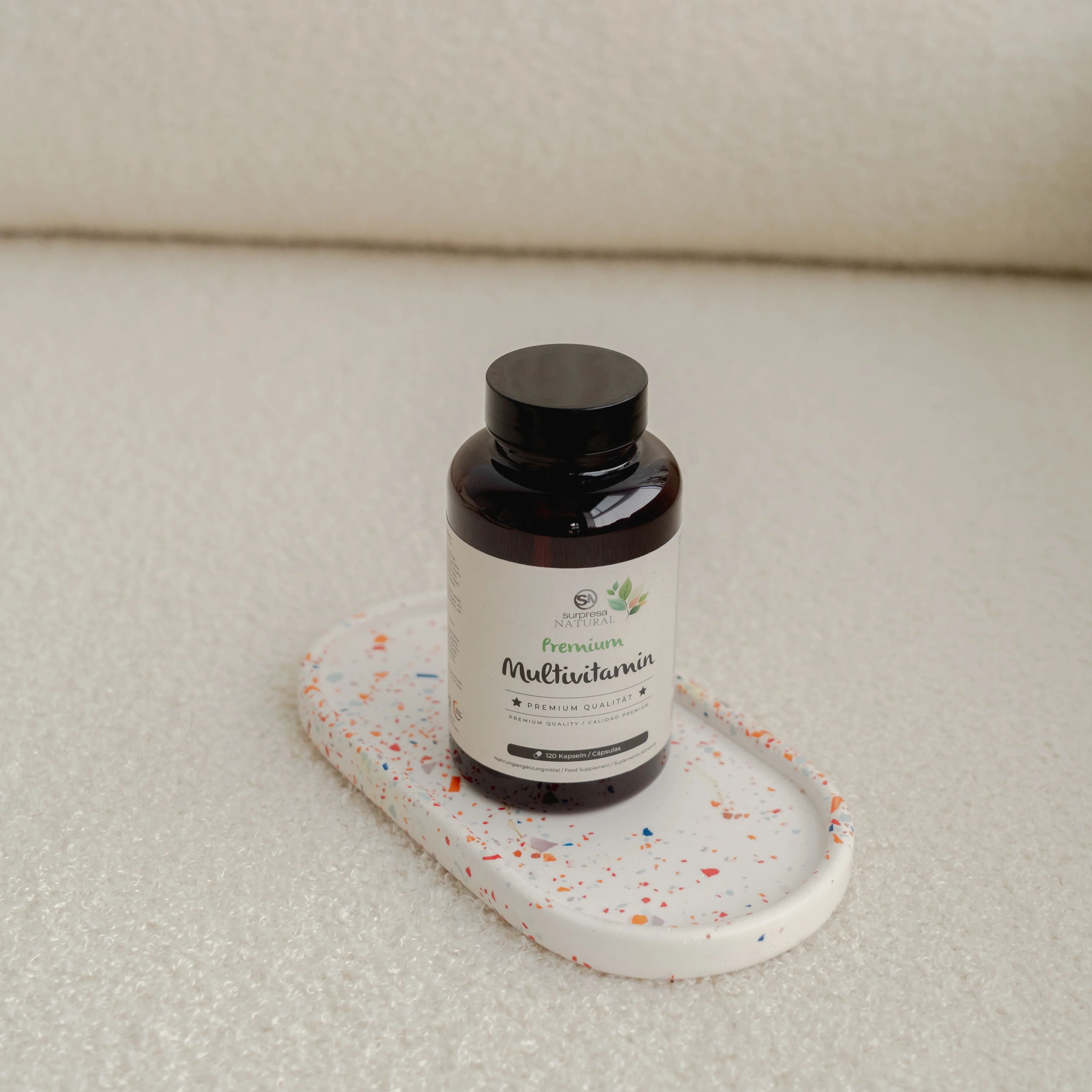Braune Flasche mit Etikett auf einem Tablett. Aufschrift: Surpresa Natural Multivitamin. Schwarzer Deckel.