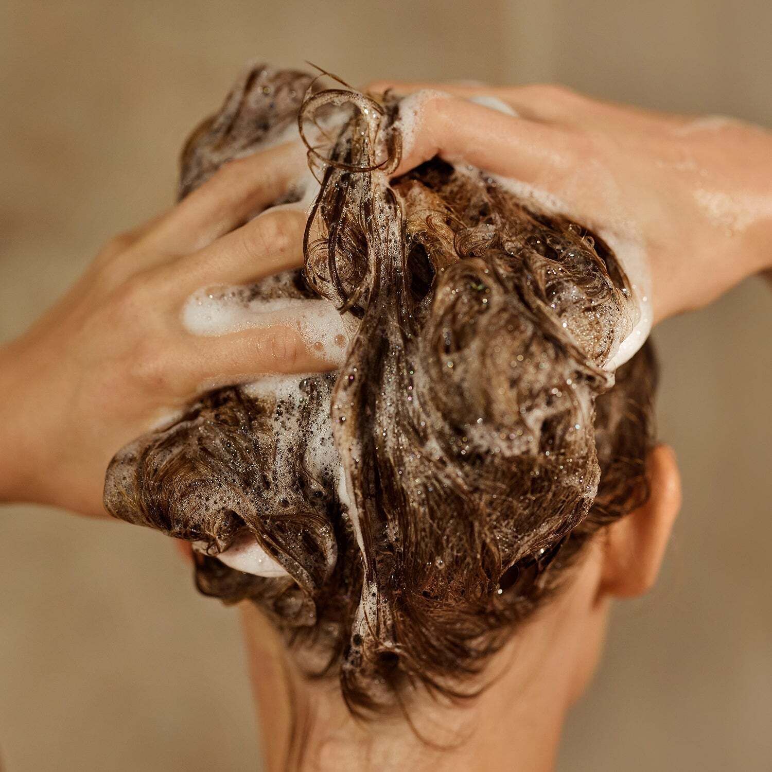Hände waschen Haare mit Shampoo. Schaum bedeckt das Haar. Rückansicht einer Person.