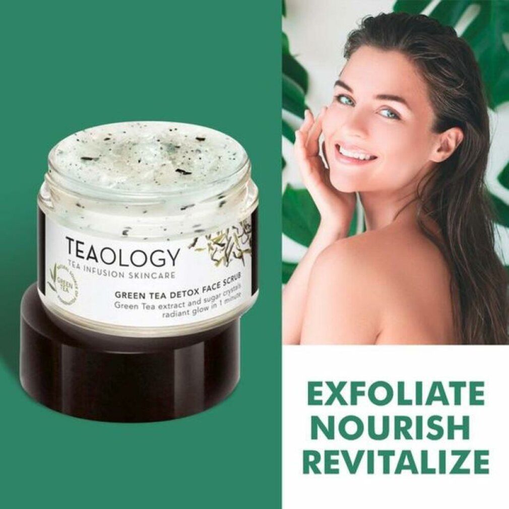 Teaology Green Tea Detox Face Scrub in einem Glasbehälter mit schwarzem Deckel. Der Scrub enthält grüne Teeblätter.