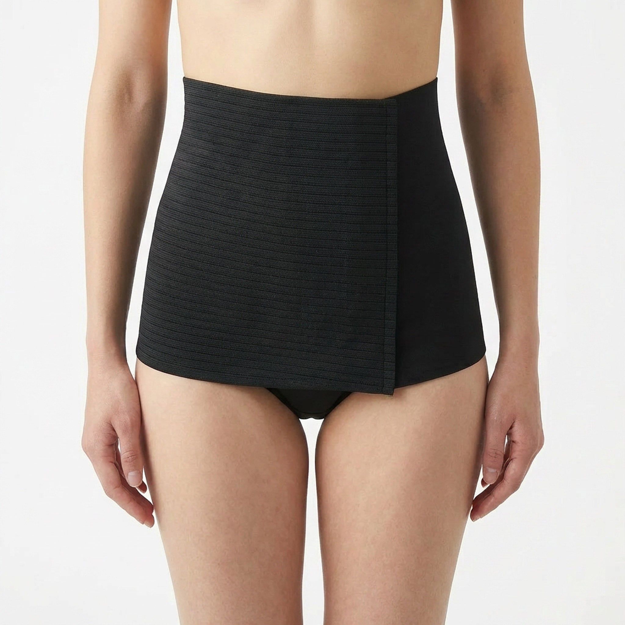 Schwarzer Bauchgürtel, geripptes Design, seitlicher Verschluss. Am Körper einer Frau getragen.