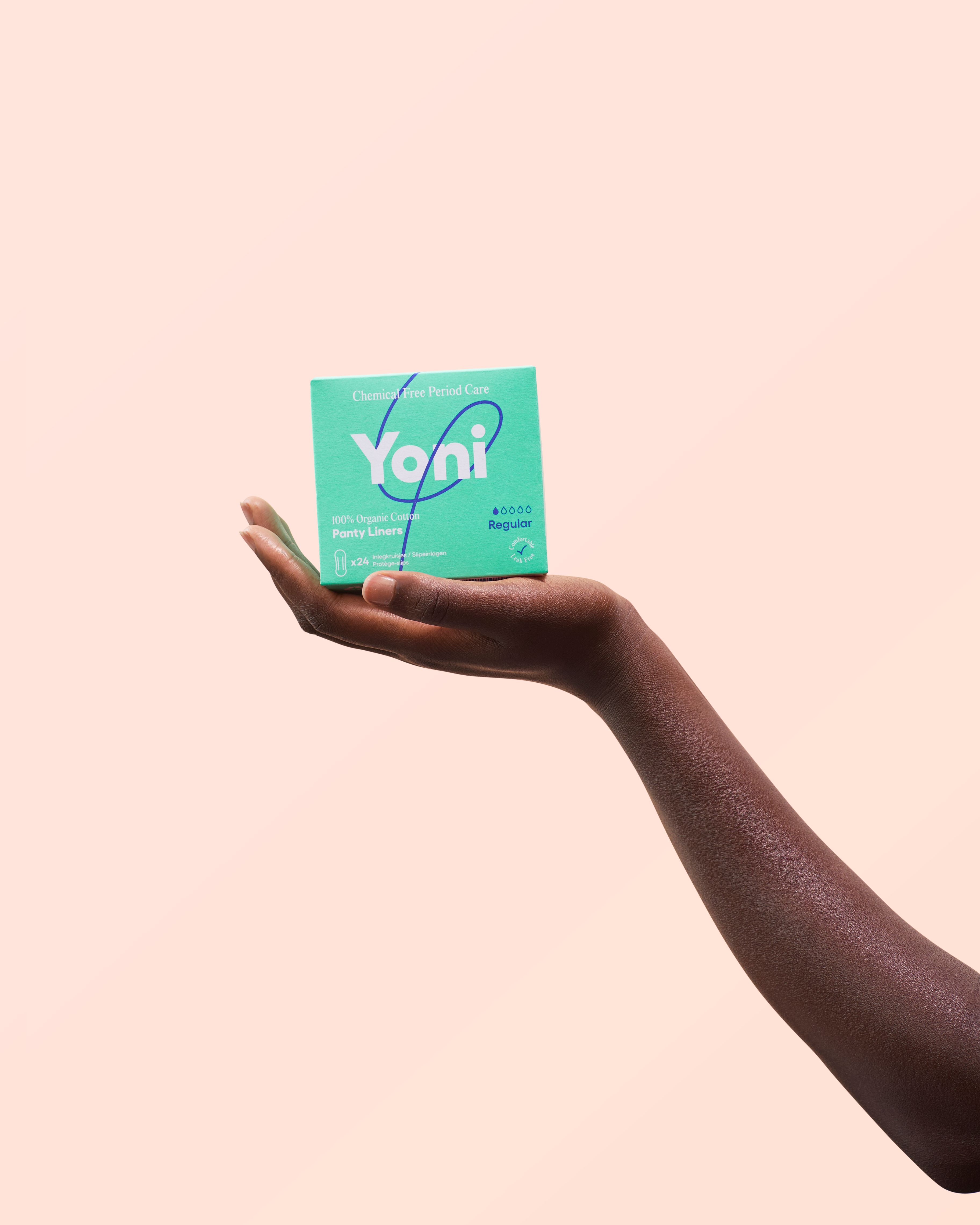 Hand hält eine grüne Yoni-Verpackung. Aufschrift: Chemical Free Period Care, Regular, 100% Organic Cotton Panty Liners.