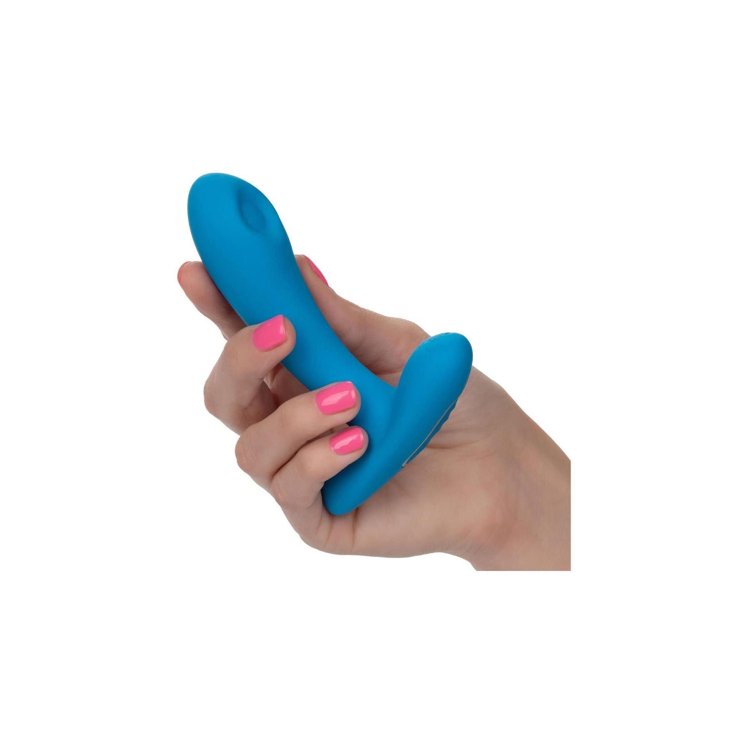 Blauer Silikon-Pleaser in einer Hand gehalten. Rosa lackierte Fingernägel. Produkt aus Silikon.