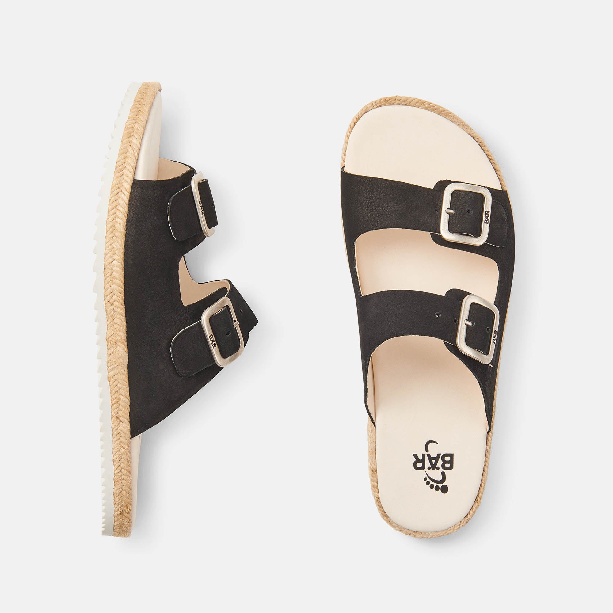 Zwei Pantoletten, eine von oben, eine von der Seite. Schwarzes Obermaterial, beige Innensohle, geflochtener Rand.