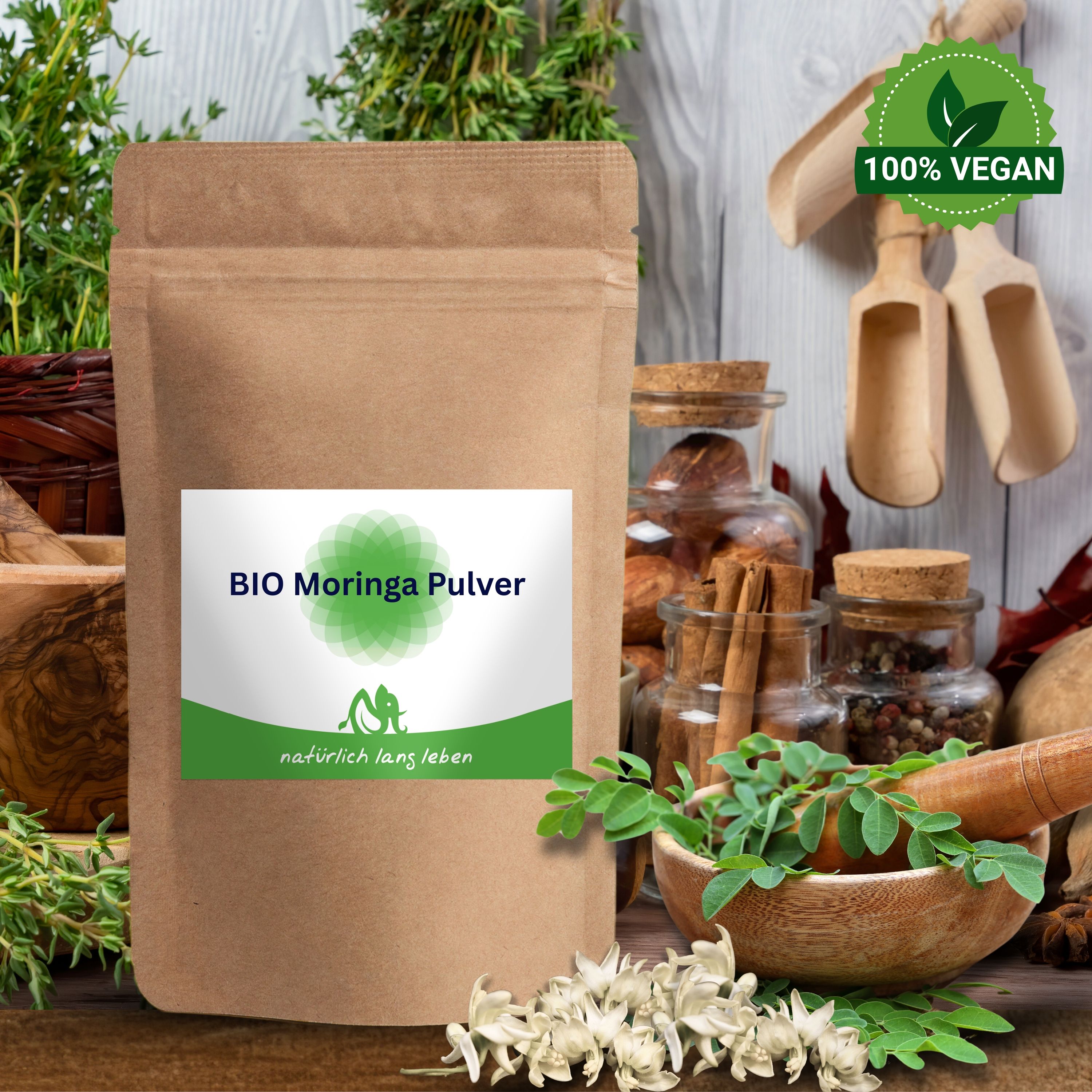 Braune Tüte mit Etikett. Aufschrift: BIO Moringa Pulver. Logo. Im Hintergrund: Kräuter, Gläser, Holzschalen, 100% Vegan-Siegel.