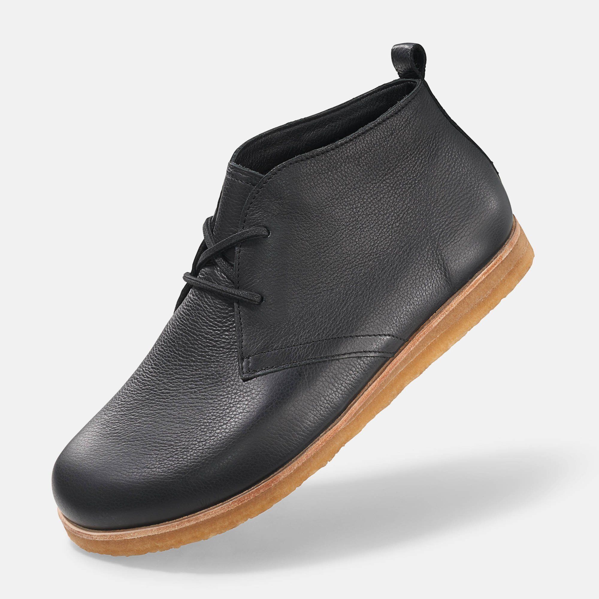 Schwarze Stiefelette mit Schnürung und heller Sohle. Schuh von der Seite, leicht erhöht.