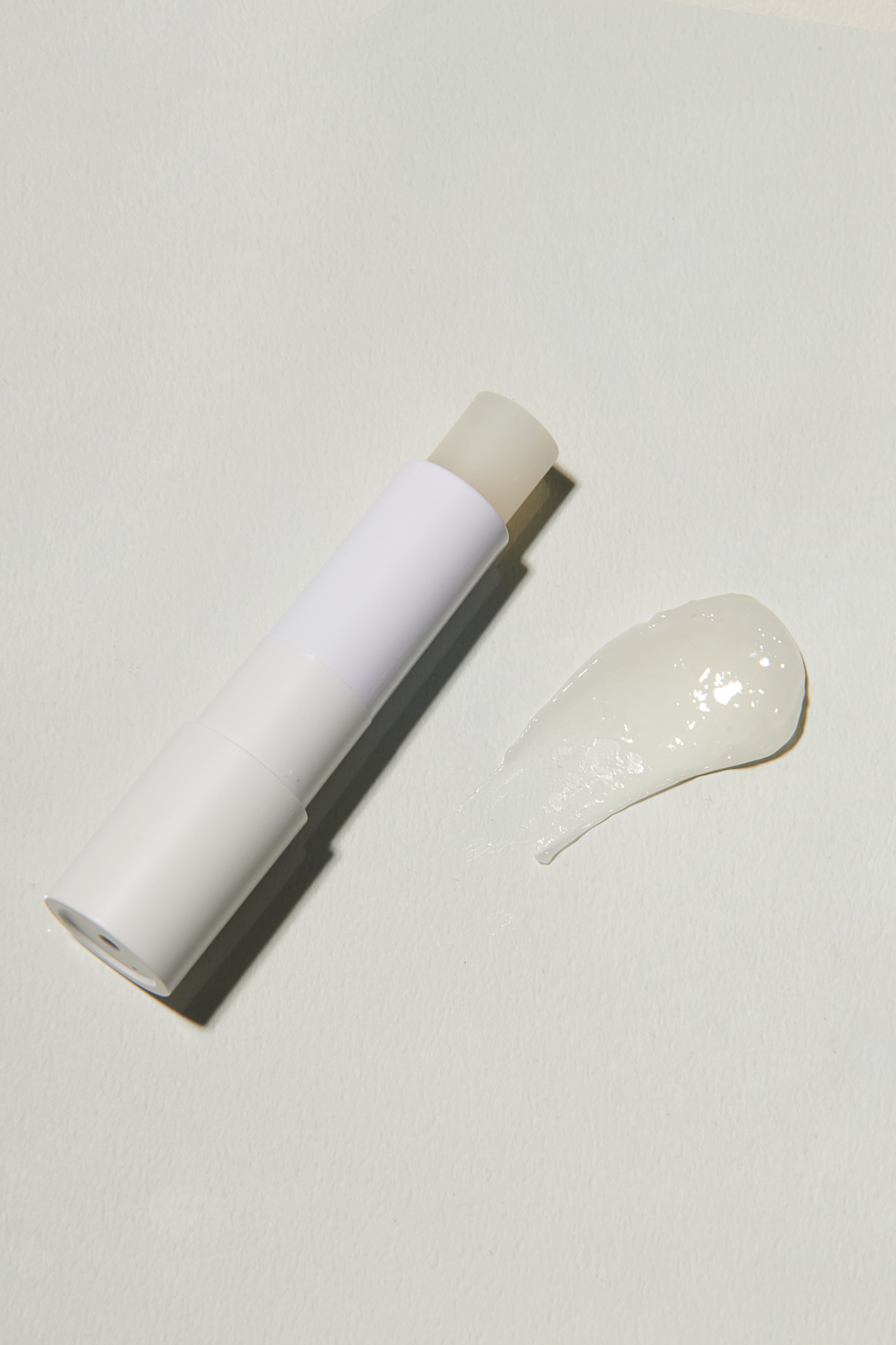 Weißer Lippenbalsam-Stick und eine Spur des Produkts. Der Stick ist geöffnet.