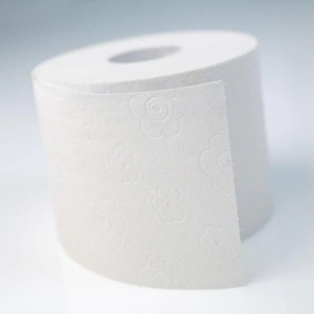 Toilettenpapierrolle mit floralem Muster. Weißes Papier, teilweise abgerollt.