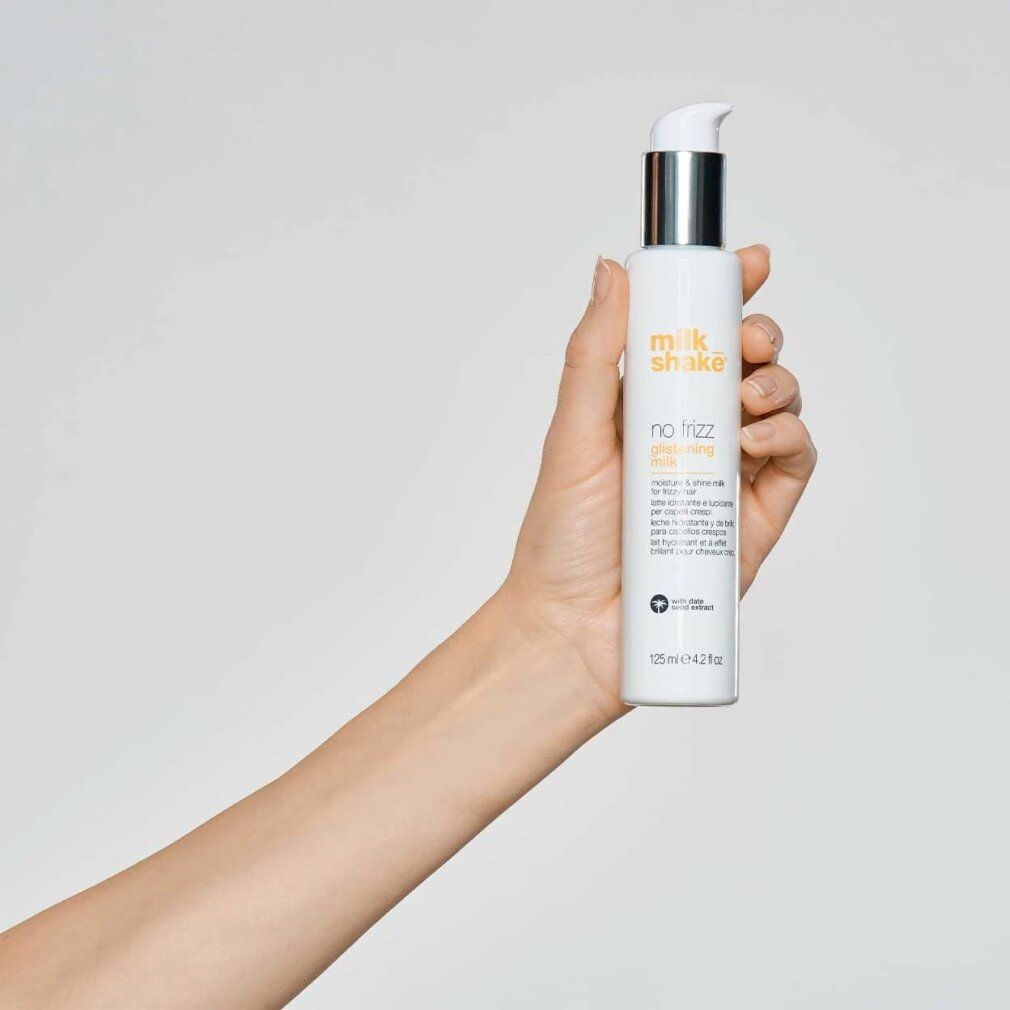 Weißes Produkt in einer Hand gehalten. Aufschrift: Milk_Shake, No Frizz Glistening Milk. Mehrsprachige Produktbeschreibung. Unten: 125 ml.