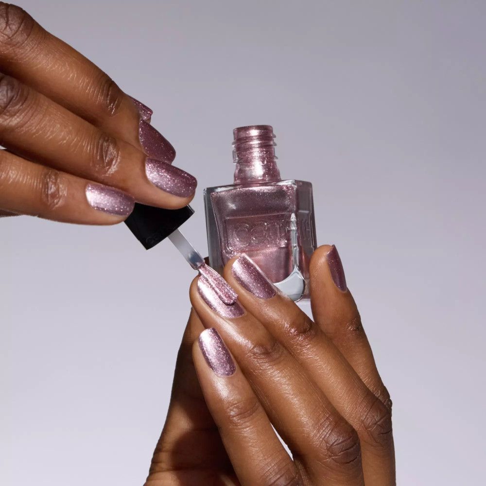 Hände mit Nagellack. Eine Hand hält eine Nagellackflasche, die andere lackiert einen Nagel.