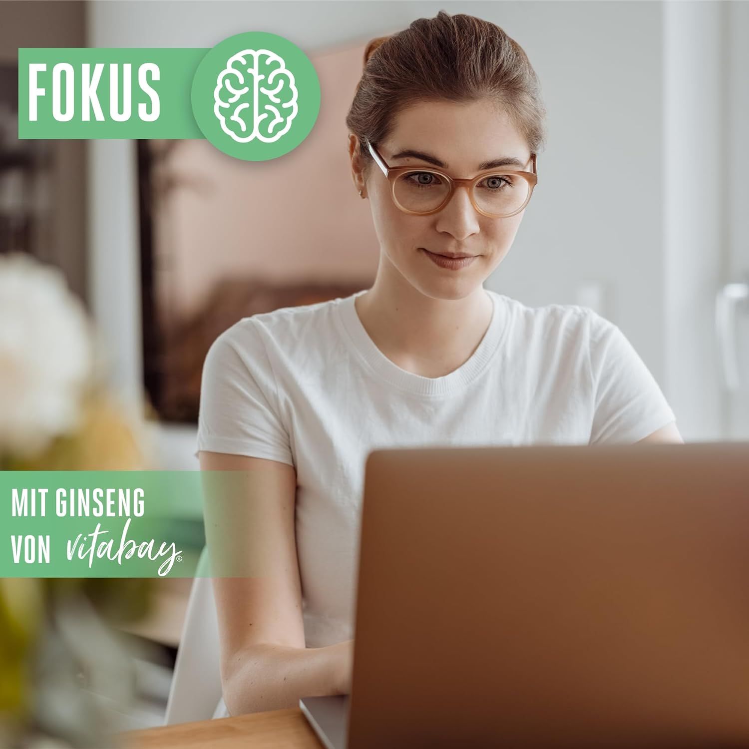 Frau mit Brille sitzt vor einem Laptop. Text: Fokus. Text: Mit Ginseng von Vitabay.
