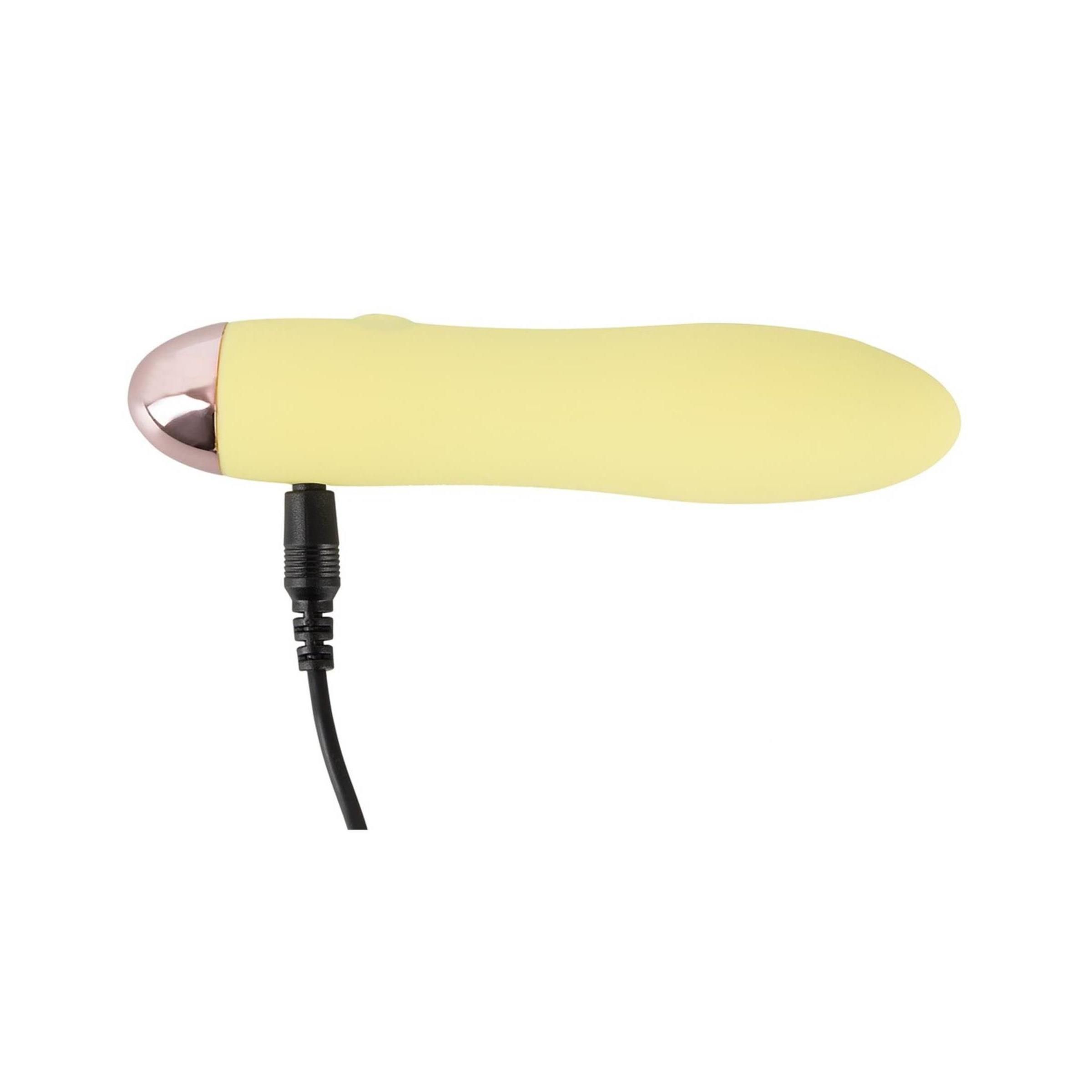 Gelber Vibrator mit Ladekabel. Rosa Spitze, glatte Oberfläche.