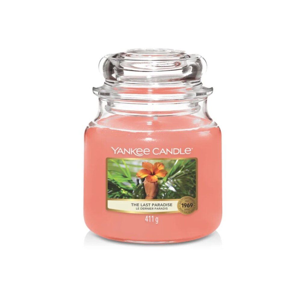 Yankee Candle Duftkerze, Medium, The Last Paradise. Rosa Wachs in Glasbehälter mit Deckel. Etikett mit Blüte und Text.