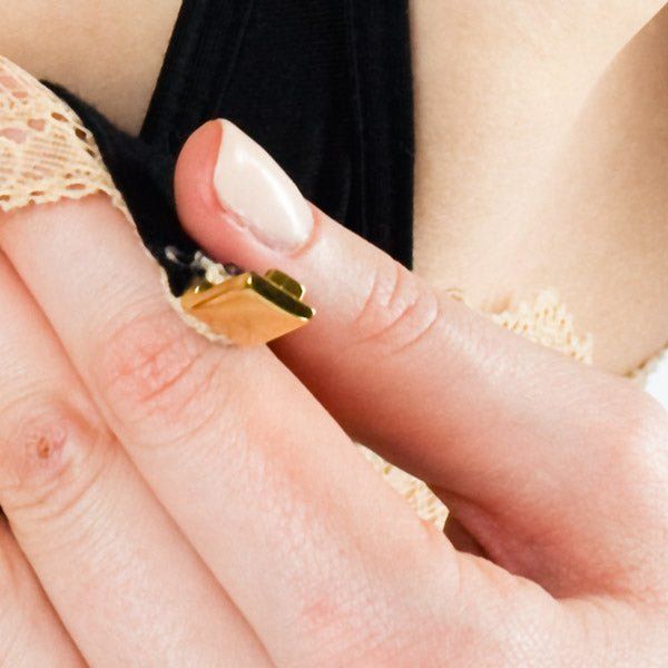 Nahaufnahme des BH-Verschlusses. Goldfarbenes Metall. BH-Spitze und Haut im Hintergrund.