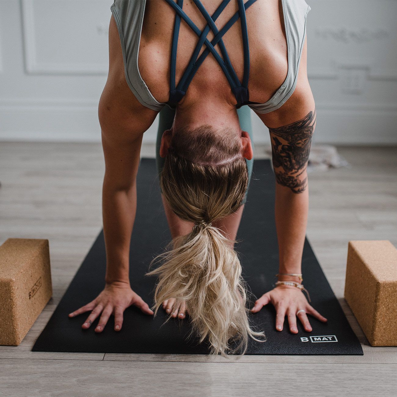 Person in Yoga-Pose auf schwarzer Yogamatte. Zwei Yogablöcke liegen neben der Matte.