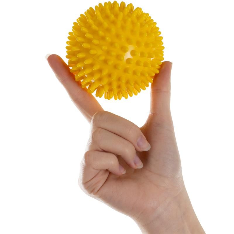 Gelbe Massagekugel mit Noppen, gehalten in einer Hand. Die Kugel ist rund und hat spitze Erhebungen.